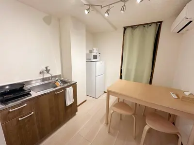 a kitchen with a sink and a table and a refrigerator at The Travelers Court Bunkyo III in Tokyo