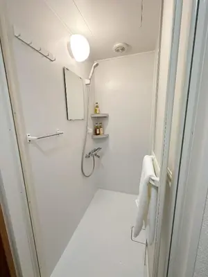 a white bathroom with a shower and a mirror at The Travelers Court Bunkyo III in Tokyo