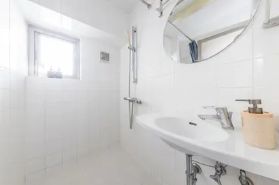 a white bathroom with a sink and a mirror at WASABI Shibuya in Tokyo