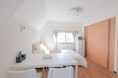 a bedroom with a bed and a white table and chairs at \u65b0\u5bbf\u99c5\u30a8\u30ea\u30a2\u5f92\u6b69\u570f \u4ea4\u901a\u81f3\u4fbf \u89b3\u5149 \u30b7\u30e7\u30c3\u30d4\u30f3\u30b0 \u30b0\u30eb\u30e1\u306b\u6700\u9069\u306a\u5317\u65b0\u5bbf\u30b9\u30c6\u30a4 So1g in Tokyo