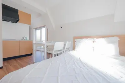 a large white bed in a room with a table at \u65b0\u5bbf\u99c5\u30a8\u30ea\u30a2\u5f92\u6b69\u570f \u4ea4\u901a\u81f3\u4fbf \u89b3\u5149 \u30b7\u30e7\u30c3\u30d4\u30f3\u30b0 \u30b0\u30eb\u30e1\u306b\u6700\u9069\u306a\u5317\u65b0\u5bbf\u30b9\u30c6\u30a4 So1g in Tokyo