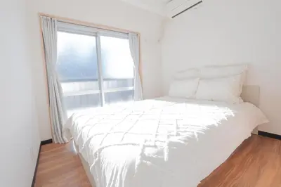 a white bed in a room with a large window at \u65b0\u5bbf\u99c5\u30a8\u30ea\u30a2\u5f92\u6b69\u570f \u4ea4\u901a\u81f3\u4fbf \u89b3\u5149 \u30b7\u30e7\u30c3\u30d4\u30f3\u30b0 \u30b0\u30eb\u30e1\u306b\u6700\u9069\u306a\u5317\u65b0\u5bbf\u30b9\u30c6\u30a4 So1g in Tokyo