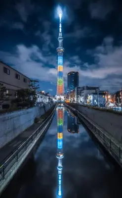a tall tower with a reflection in the water at night at \u7f8e-yahiro- in Tokyo
