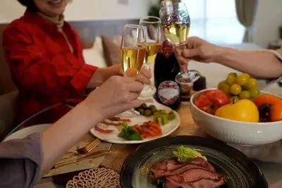two people holding glasses of wine at a table with food at Nuan Stay Tokyo in Tokyo