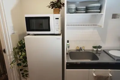 a microwave on top of a refrigerator next to a sink at Nuan Stay Tokyo in Tokyo