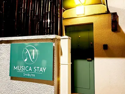 a sign in front of a building with a green door at Shibuya 10 min Walk Theater & Garden Stay Max 6ppl in Tokyo