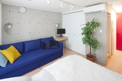 a blue couch in a living room with a clock at 306 5 mins train to Roppongi , direct bus to Shibuya in Tokyo