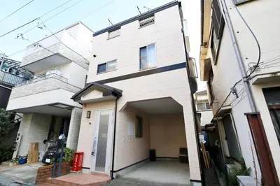 a white building with a garage in front of it at Cozy house Tokyo in Tokyo