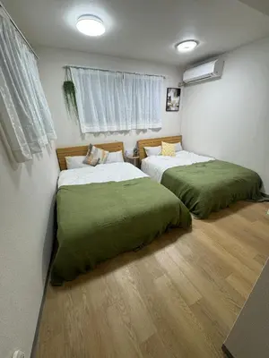a bedroom with two beds with green sheets at \u5c71\u624b\u7dda\u5927\u585a in Tokyo