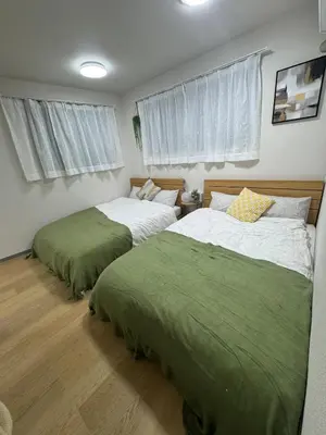 two beds in a bedroom with green sheets at \u5c71\u624b\u7dda\u5927\u585a in Tokyo