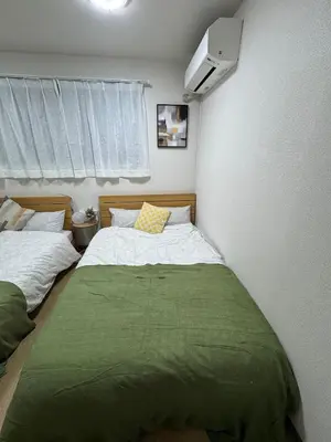 a bedroom with two beds and a tv on the wall at \u5c71\u624b\u7dda\u5927\u585a in Tokyo