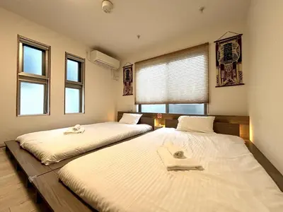 two twin beds in a room with windows at Yama Hotel Otsuka in Tokyo