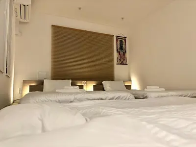 three white beds in a room with a window at Yama Hotel Otsuka in Tokyo