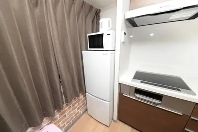 a small kitchen with a refrigerator and a microwave at NY House 2\u65b0\u5bbf\u4e09\u968e\u5efa\u30663\u5ba42\u30b7\u30e3\u30ef\u30fc2\u30c8\u30a4\u30ec in Tokyo