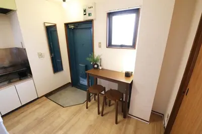 a small kitchen with a table and two stools at Shitamachi Skyroom in Yotsugi Private Room in Tokyo