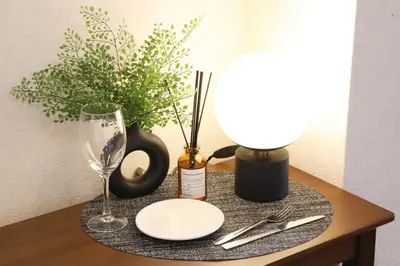 a table with a lamp and a plate and a wine glass at Shitamachi Skyroom in Yotsugi Private Room in Tokyo