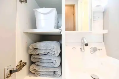 a bathroom with towels on a shelf next to a sink at Tanuki Apartment Shinjuku West in Tokyo