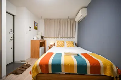 a bedroom with a bed with a colorful striped blanket at Home Story in Tokyo Uguisudani\u30e9\u30a4\u30ba\u65e5\u66ae\u91cc \u6771\u4eac\u5c4b\u8a9e in Tokyo