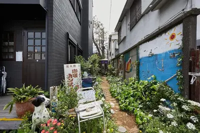 a garden with a chair and flowers next to a building at Dreamy Music Cafe Bar in Tokyo