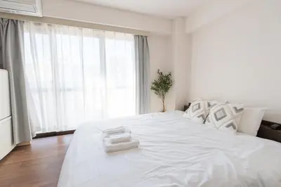 a white bed in a room with a large window at Oji Inn \u738b\u5b50\u30a4\u30f3 in Tokyo
