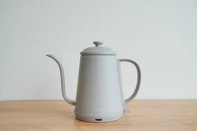 a white tea kettle sitting on a wooden table at Mari Hotel in Tokyo