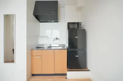 a kitchen with a black refrigerator and a sink at Mari Hotel in Tokyo