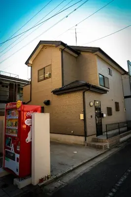 a house with a soda machine in front of a building at J's Backpackers in Tokyo