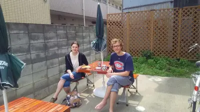 two women sitting at a table on a patio at J's Backpackers in Tokyo