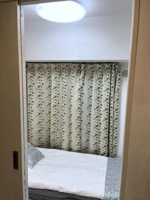 a small bed in a small room with a curtain at \u6d45\u8349\u6c11\u6cca301 in Tokyo