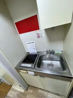 a kitchen with a sink and a red and white wall at \u6d45\u8349\u6c11\u6cca303 in Tokyo