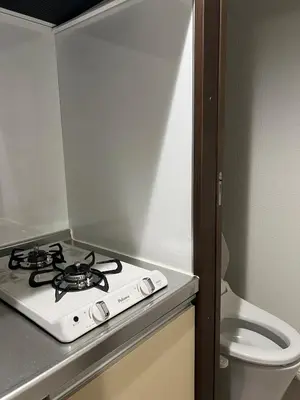 a stove top in a small kitchen with a toilet at Apartment Hotel in Katsushika City in Tokyo