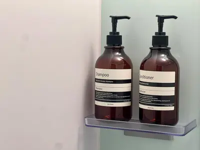 two bottles of shampoo are sitting on a shelf at Apartment Hotel in Katsushika City in Tokyo