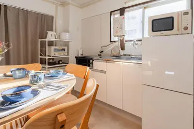 a kitchen with a table and a white refrigerator at HouseHotel\u4e94\u53cd\u7530 in Tokyo
