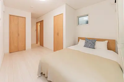 a white bedroom with a large bed and wooden cabinets at Newly Built 4-Bedroom House in Shopping Street, 8-Min Walk from Akabane Station in Tokyo