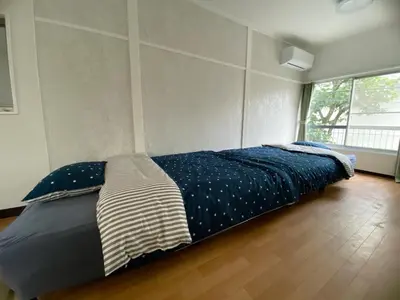 a bedroom with a bed with blue sheets and a window at Core of Tokyo, 30 mins from Shinjuku & Ueno, LARGE in Tokyo