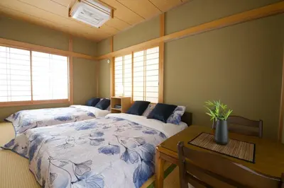 a bedroom with two beds and a table and windows at Peace House in Tokyo