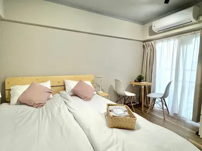 a bedroom with a bed with white sheets and pink pillows at ShinjukuCityStay 502 in Tokyo