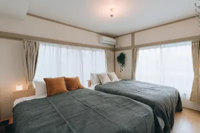 a bedroom with two beds and a large window at Tokyo Nest Ohana in Tokyo
