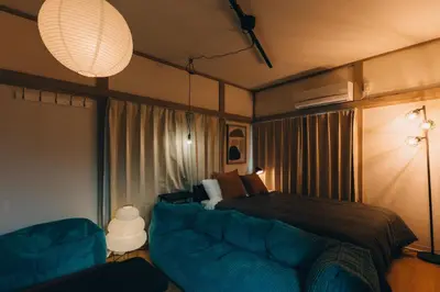 a bedroom with a bed and a couch and a lamp at Tokyo Nest Ohana in Tokyo