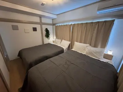 two beds in a small room with a window at Tokyo Nest Ohana in Tokyo