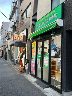 a store with a green sign on the side of a street at Louis stage showamachi in Tokyo