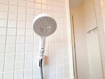 a white blow dryer in a bathroom with white tiles at 301, 6 min walk to subway stn, Tokyo Univ, Tokyo Tower, Tokyo-Dome direct by subway in Tokyo