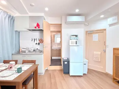 a kitchen with a table and a white refrigerator at 301, 6 min walk to subway stn, Tokyo Univ, Tokyo Tower, Tokyo-Dome direct by subway in Tokyo