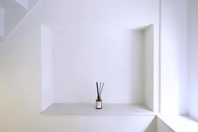 a white room with a small vase with sticks in it at Group Friendly - Prime 3BR - Great Location & Rooftop in Tokyo
