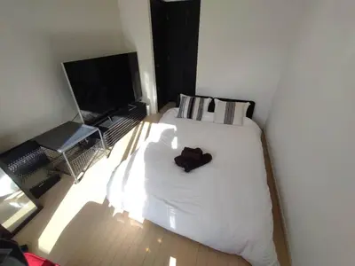 a bedroom with a white bed and a flat screen tv at New open \u6e0b\u8c37\u99c5\u5f92\u6b695\u5206 \u90fd\u5fc3\u3078\u306e\u629c\u7fa4\u306e\u30a2\u30af\u30bb\u30b9 2\u540d\u307e\u3067\u5bbf\u6cca\u53ef\u80fd in Tokyo