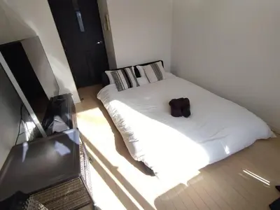a bedroom with a white bed with a brown bag on it at New open \u6e0b\u8c37\u99c5\u5f92\u6b695\u5206 \u90fd\u5fc3\u3078\u306e\u629c\u7fa4\u306e\u30a2\u30af\u30bb\u30b9 2\u540d\u307e\u3067\u5bbf\u6cca\u53ef\u80fd in Tokyo
