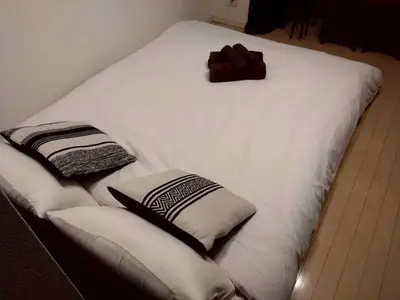 a white bed with two pillows on top of it at New open \u6e0b\u8c37\u99c5\u5f92\u6b695\u5206 \u90fd\u5fc3\u3078\u306e\u629c\u7fa4\u306e\u30a2\u30af\u30bb\u30b9 2\u540d\u307e\u3067\u5bbf\u6cca\u53ef\u80fd in Tokyo