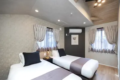 two beds in a hotel room with windows at Bijou Suites Zephyr in Tokyo