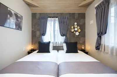 two beds in a room with two windows at Bijou Suites Zephyr in Tokyo