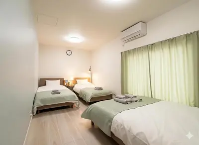 a room with two beds and a clock on the wall at APRO STAY\u7fbd\u7530 garden7 201\u53f7\u5ba4 in Tokyo